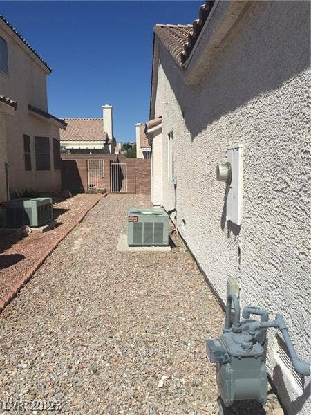 Gravel pathways flank the stucco exterior beneath clear desert skies.