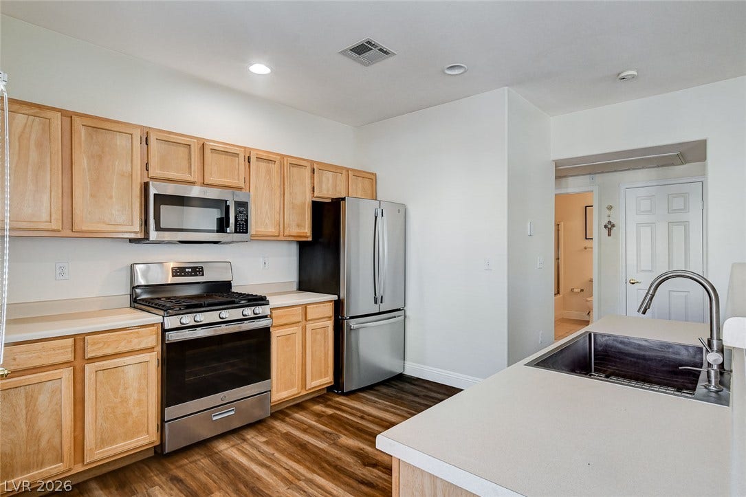 1520 Ruby Cliffs Lane, #203, Las Vegas, NV 89144 Warm wood cabinetry and modern appliances frame this functional kitchen layout.