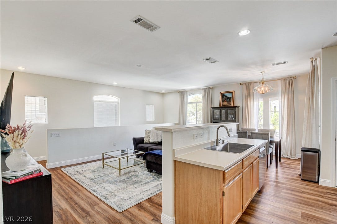 1520 Ruby Cliffs Lane, #203, Las Vegas, NV 89144 Warm wood flooring flows seamlessly through an open concept kitchen, living, and dining layout.