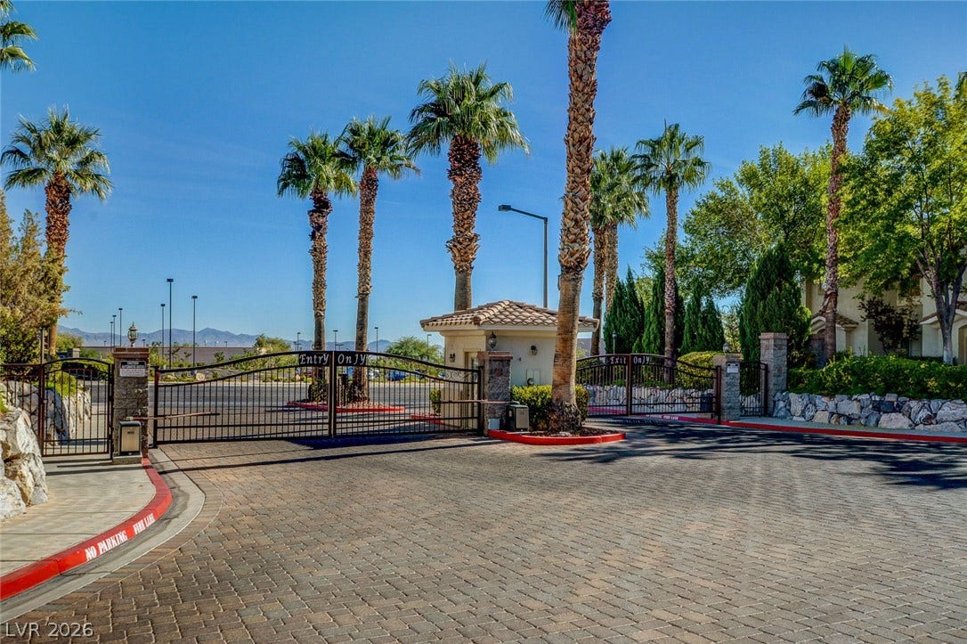 1520 Ruby Cliffs Lane, #203, Las Vegas, NV 89144 Gated entry gates framed by palm trees open to a paved driveway.