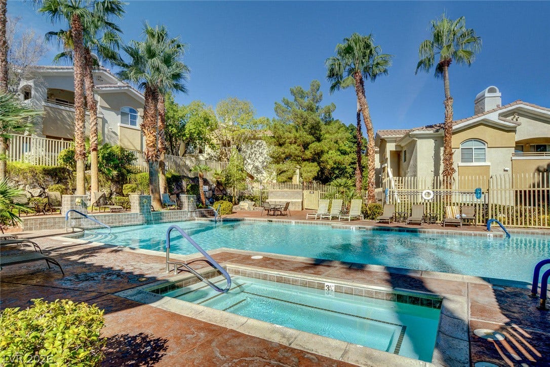 1520 Ruby Cliffs Lane, #203, Las Vegas, NV 89144 Lush palm trees frame a sparkling community swimming pool and adjacent hot tub.