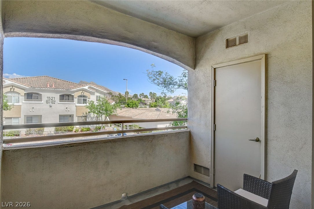 1520 Ruby Cliffs Lane, #203, Las Vegas, NV 89144 An arched opening frames a covered outdoor balcony overlooking the surrounding neighborhood structures.