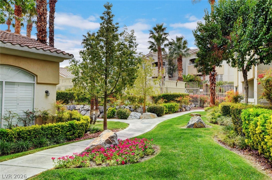 1520 Ruby Cliffs Lane, #203, Las Vegas, NV 89144 A winding concrete pathway meanders through lushly landscaped grounds shaded by mature trees.
