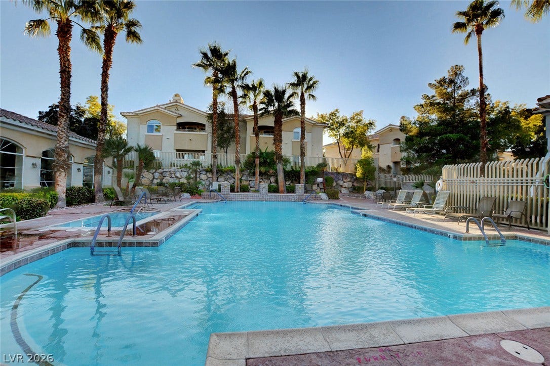 1520 Ruby Cliffs Lane, #203, Las Vegas, NV 89144 A resort-style swimming pool area is surrounded by palm trees and multi-level residential structures.