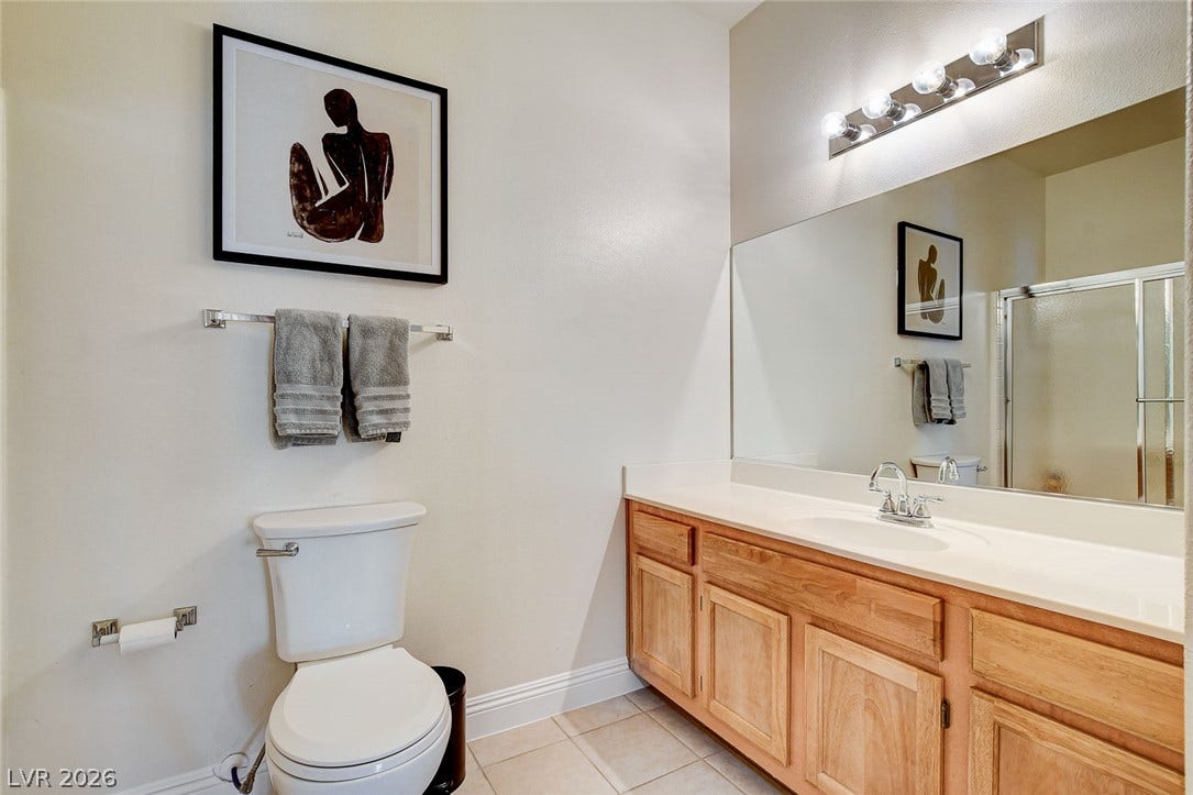 1520 Ruby Cliffs Lane, #203, Las Vegas, NV 89144 Natural wood cabinetry and neutral tile flooring anchor this functional guest bathroom.