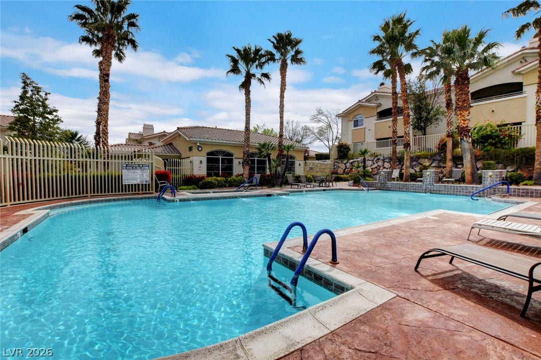 1520 Ruby Cliffs Lane, #203, Las Vegas, NV 89144 An inviting swimming pool area sits framed by towering palm trees and elegant tile roofs.
