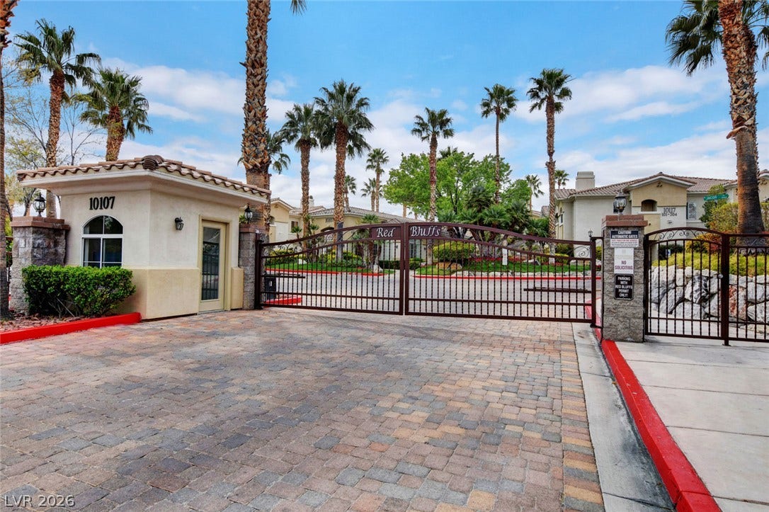 1520 Ruby Cliffs Lane, #203, Las Vegas, NV 89144 Secure gated entry features a paved driveway framed by palm trees and professional landscaping.