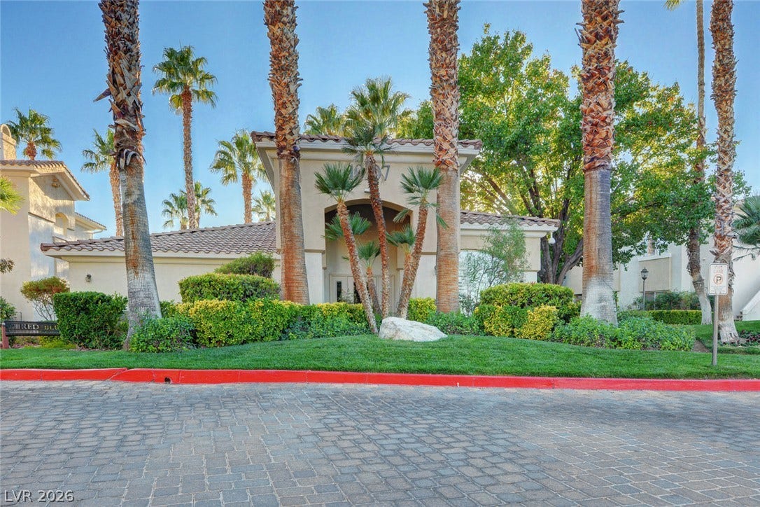 1520 Ruby Cliffs Lane, #203, Las Vegas, NV 89144 Palm trees frame the arched stucco entryway of this elegant desert estate.