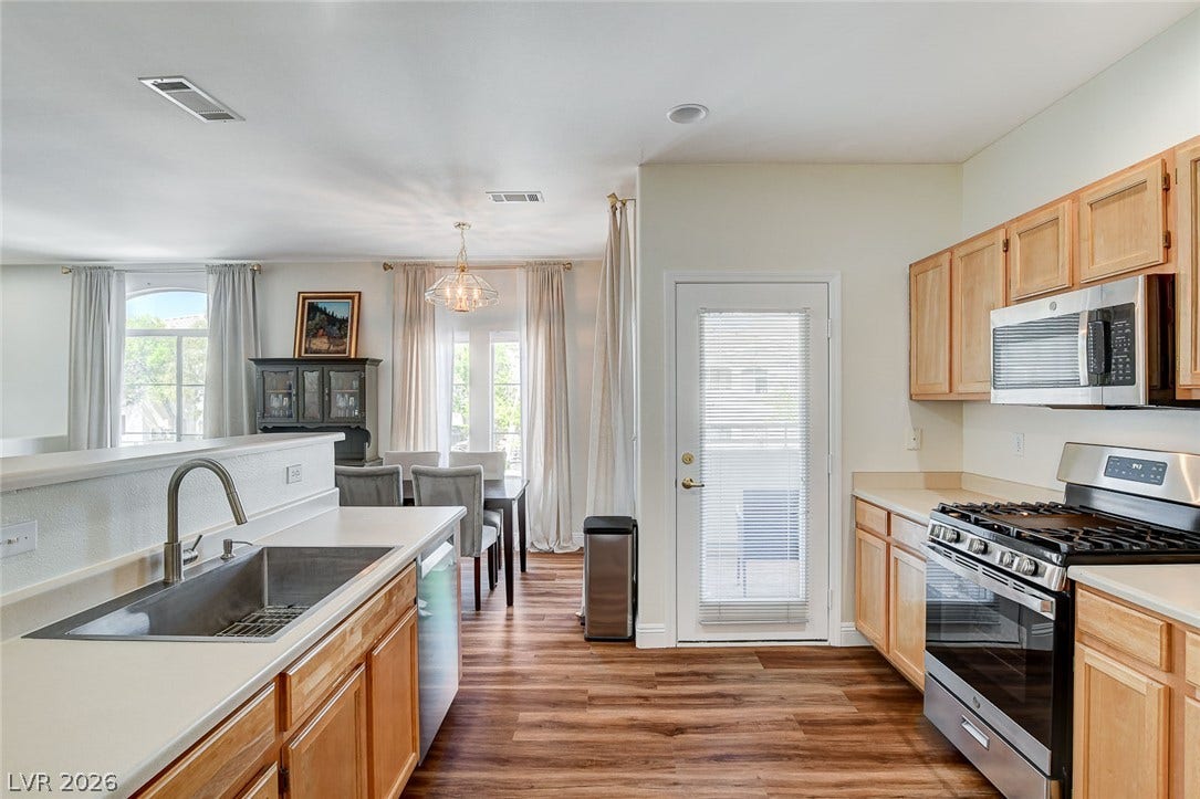 1520 Ruby Cliffs Lane, #203, Las Vegas, NV 89144 Rich wood-inspired flooring anchors this open kitchen and dining layout flowing toward glass patio doors.