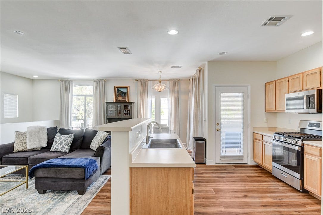 1520 Ruby Cliffs Lane, #203, Las Vegas, NV 89144 Warm wood-style flooring anchors this seamless open layout connecting the kitchen and living spaces.