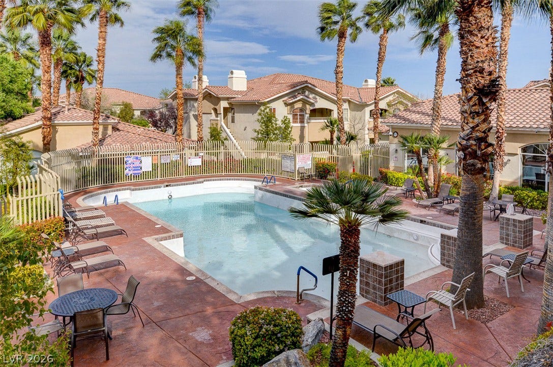 1520 Ruby Cliffs Lane, #203, Las Vegas, NV 89144 A sparkling community pool sits surrounded by palm trees and classic tile roofs.