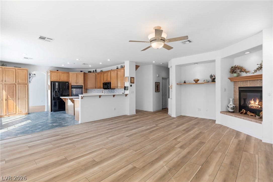 An inviting open-concept living area with light wood flooring transitions seamlessly into a well-appointed kitchen.