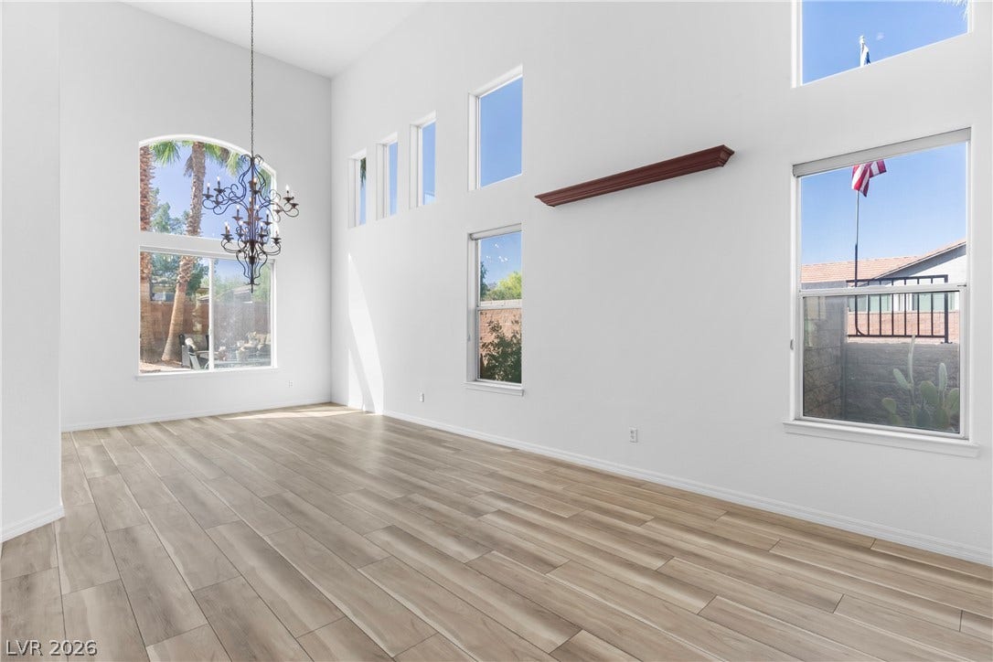 Tall ceilings and plentiful windows illuminate this expansive living space with elegant light wood flooring.