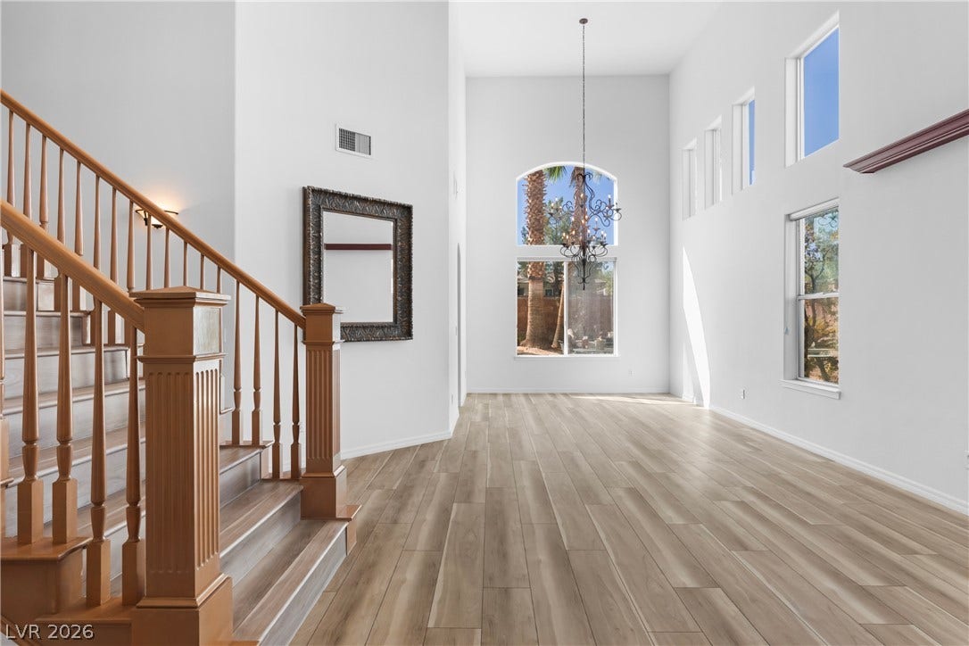 A grand two-story entryway showcases an elegant staircase and soaring ceilings, filled with natural light.