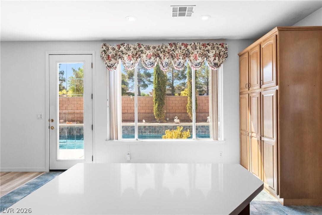 A well-lit kitchen with ample cabinet space overlooks a private pool area, perfect for daily relaxation.