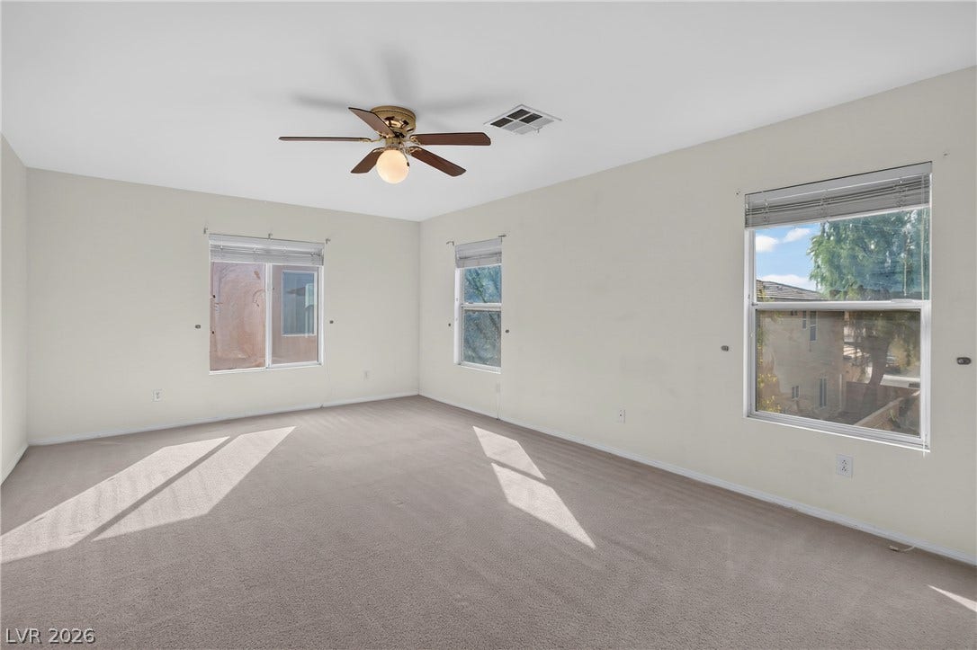 4871 Lionesse Court, Las Vegas, NV 89130 Natural light streams through multiple windows across the soft carpeting of this versatile bedroom.