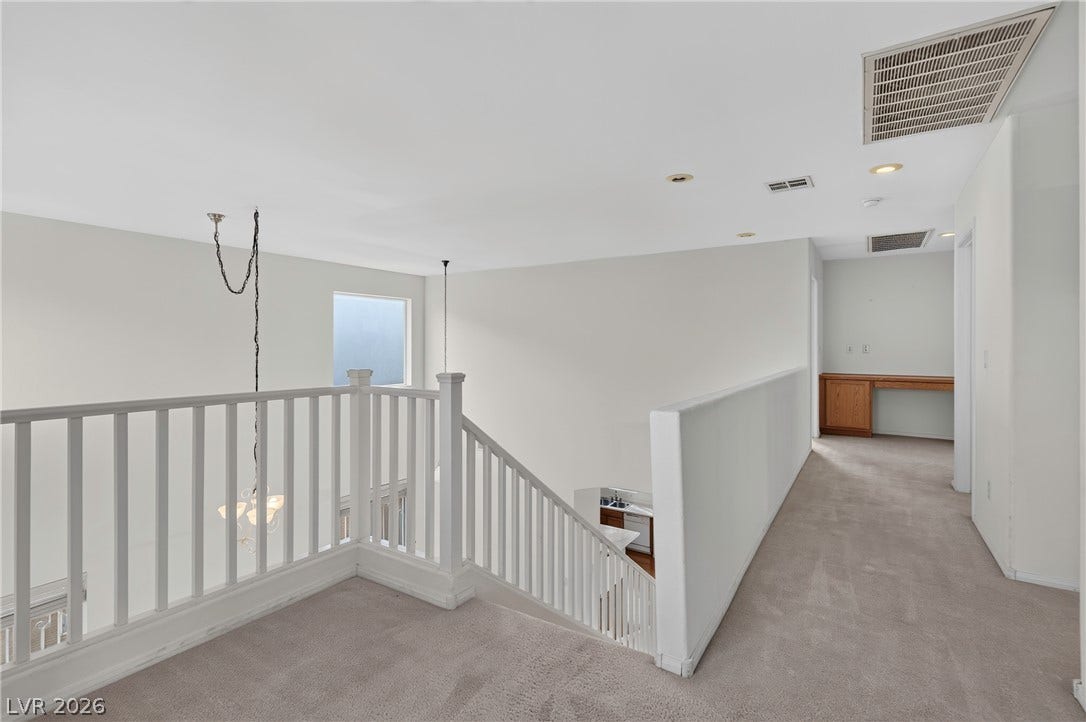 4871 Lionesse Court, Las Vegas, NV 89130 Plush carpeting and crisp white railings define this upper-level hallway overlooking the living areas below.