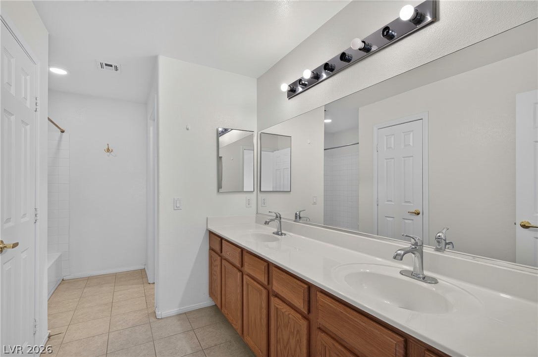 4871 Lionesse Court, Las Vegas, NV 89130 Clean lines and a spacious dual vanity highlight this classic tiled bathroom.