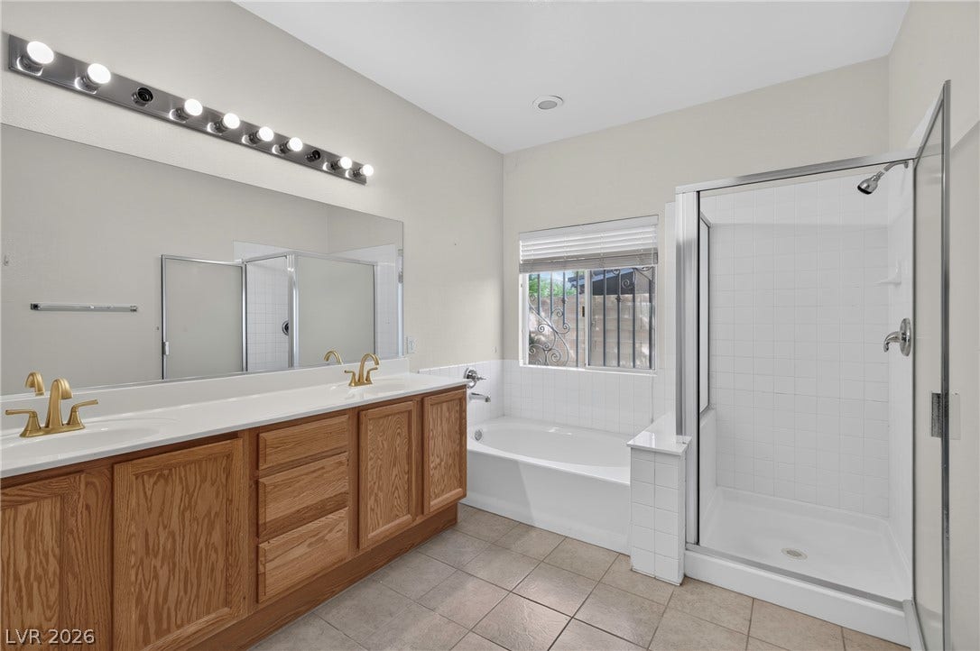 4871 Lionesse Court, Las Vegas, NV 89130 Tile flooring and a dual-sink vanity anchor this functional bathroom featuring a separate tub and shower.