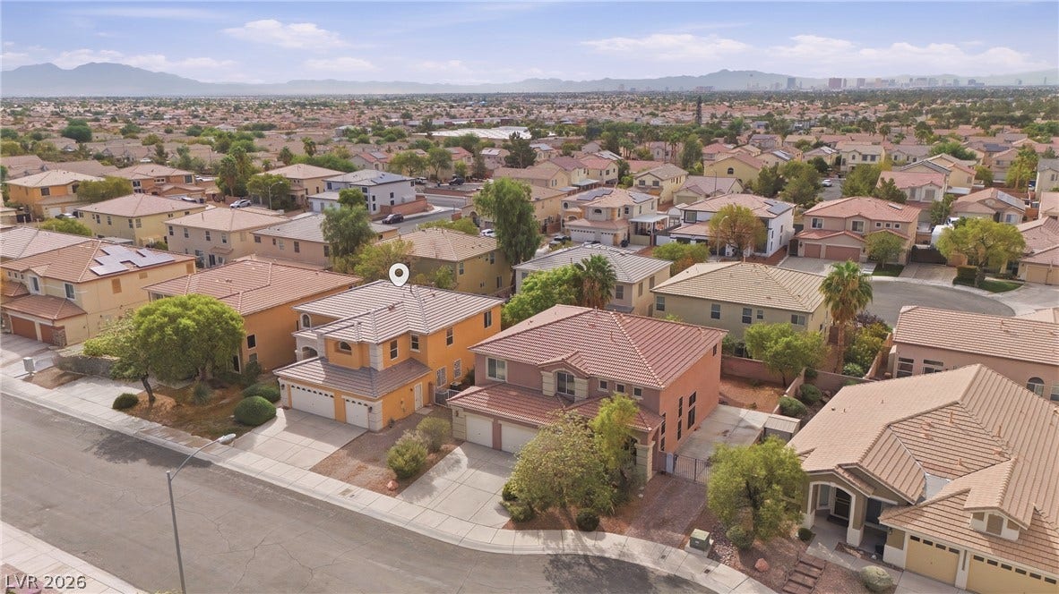 4871 Lionesse Court, Las Vegas, NV 89130 An expansive neighborhood vista unfolds beneath clear skies, revealing classic tiled roofs and distant mountains.