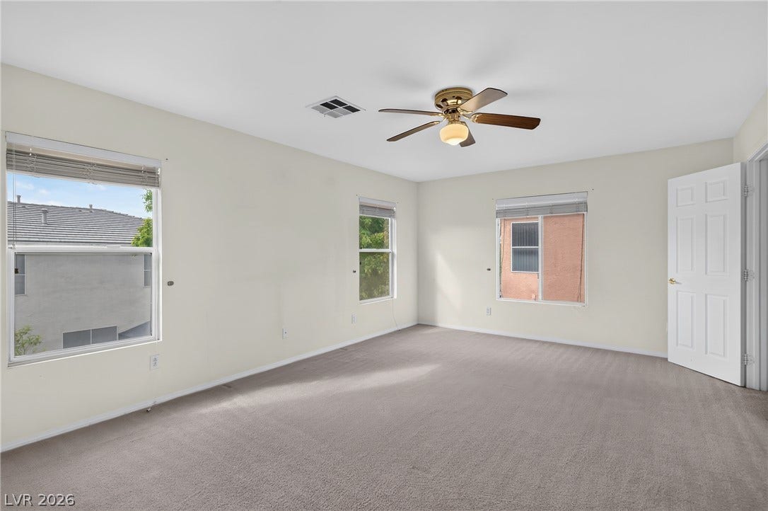4871 Lionesse Court, Las Vegas, NV 89130 Soft carpeting underfoot and multiple windows create a comfortable, well-lit bedroom atmosphere.