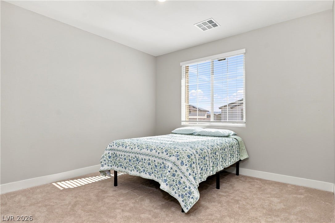 Plush carpeting and a large window anchor this peaceful secondary bedroom.