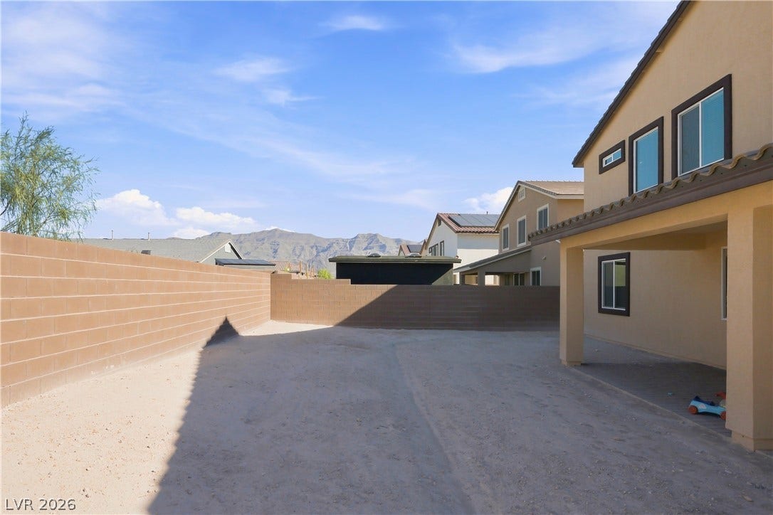 A spacious backyard area framed by privacy block walls showcases distant mountain views.