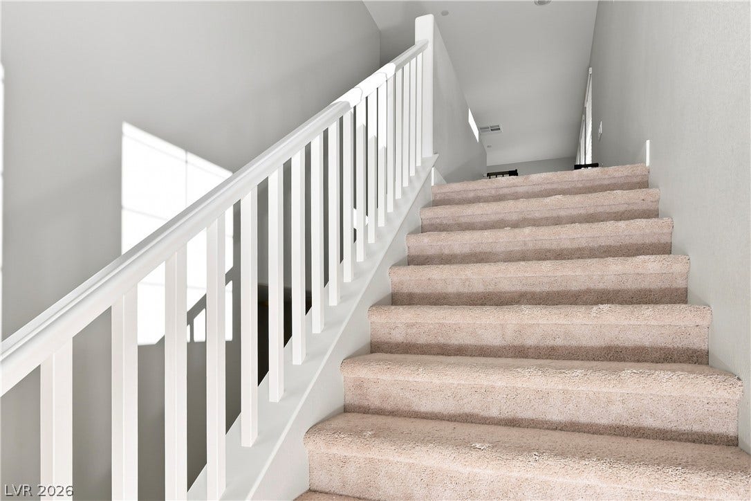 Carpeted stairs ascend alongside a classic white-balustered railing system.