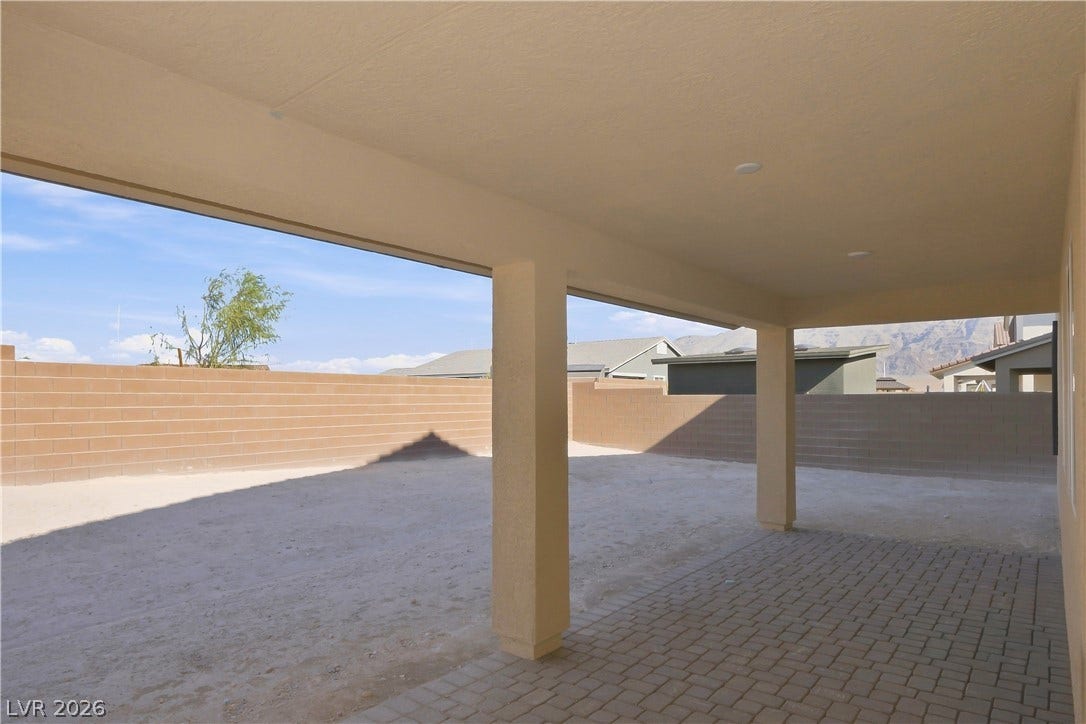 An inviting covered patio features neat brick pavers overlooking a spacious and private fenced yard.