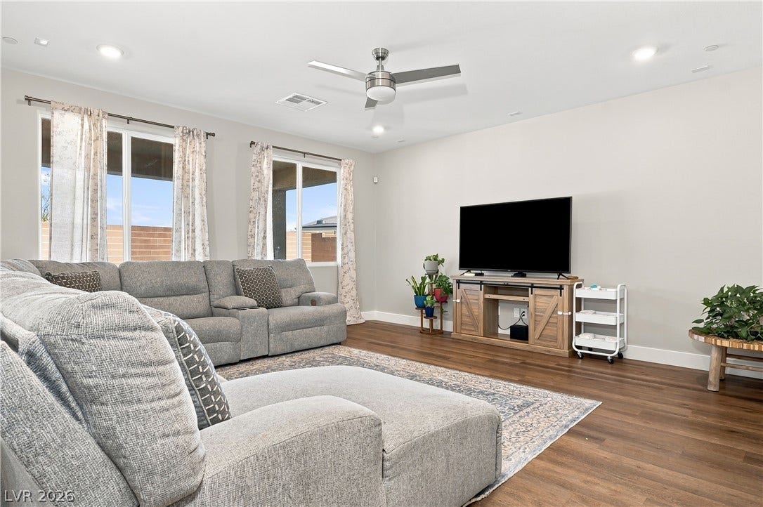 Rich wood flooring runs throughout this spacious living area illuminated by recessed lighting.