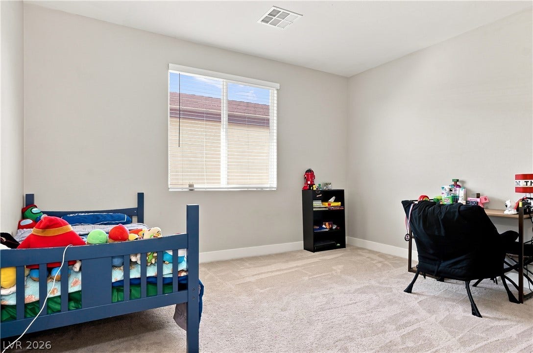 Plush carpeting and a large central window define this versatile secondary bedroom space.