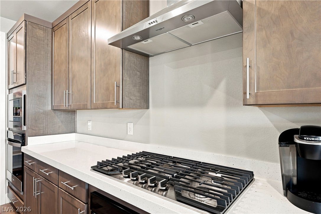 Gleaming stone countertops flank a modern gas cooktop beneath sleek wooden cabinetry.