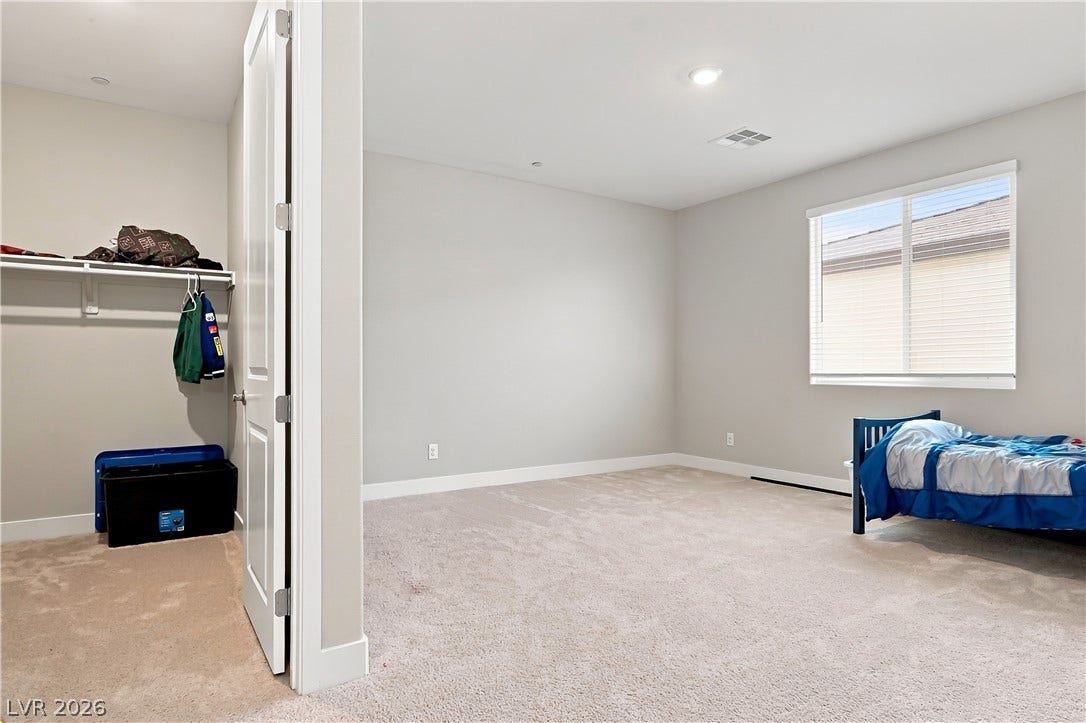 Soft carpeting pairs with recessed lighting in this comfortable space featuring a walk-in closet.