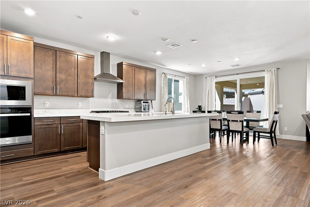Rich wood cabinetry contrasts beautifully with white stone countertops in this airy kitchen.
