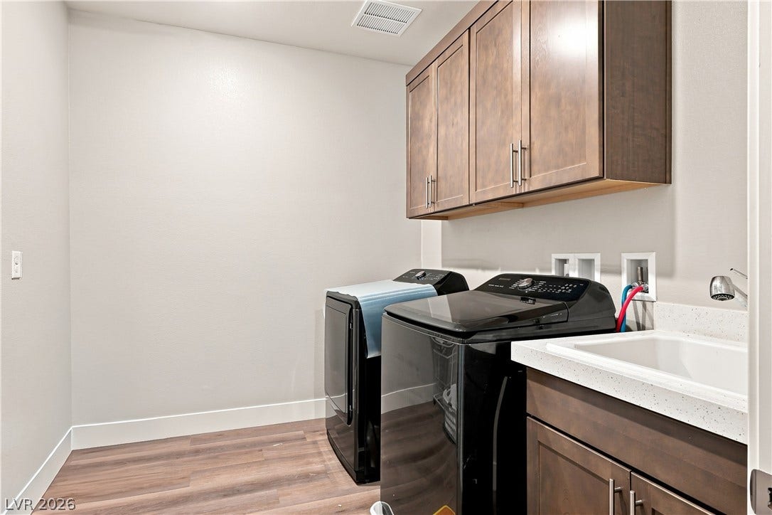 A functional laundry area includes modern cabinetry, a utility sink, and durable wood flooring.