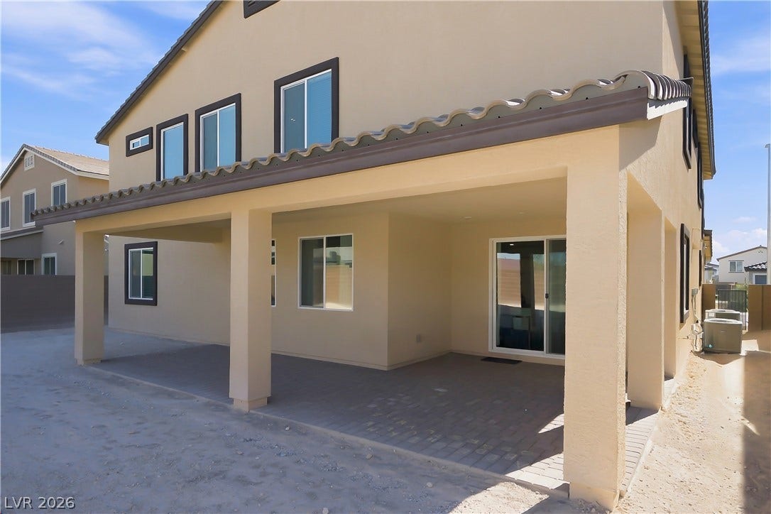 A spacious covered patio with brick pavers offers a shaded retreat alongside the home.