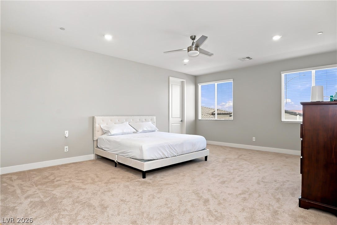 Plush carpeting and recessed lighting define this spacious bedroom layout.