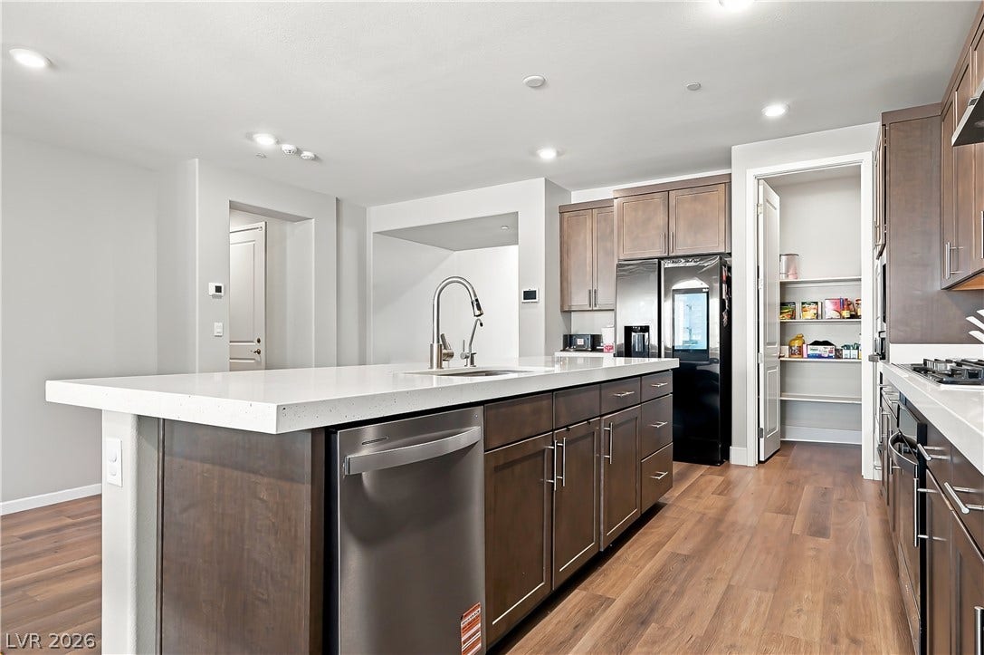 Rich wood flooring runs through this modern culinary space anchored by a stone-countertop island.