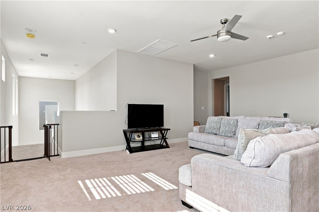 Plush carpeting anchors this versatile upstairs living space illuminated by natural light.