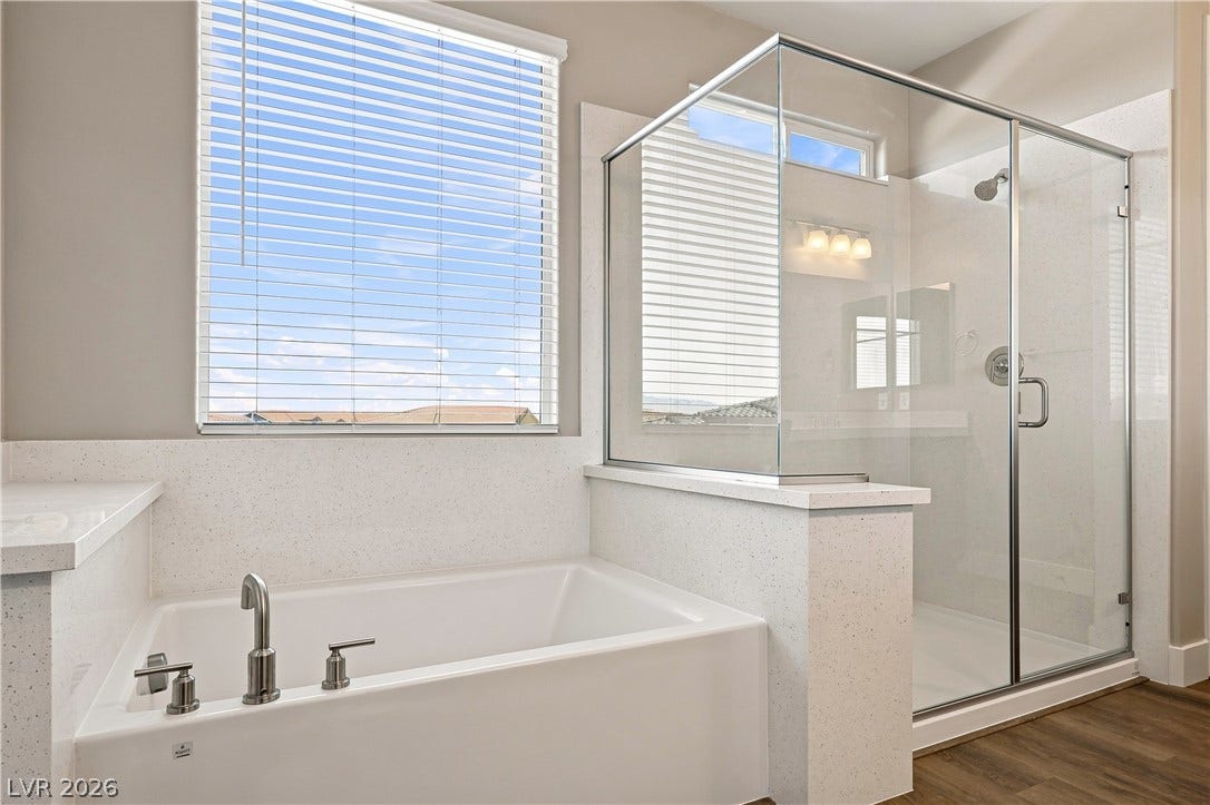 Natural light fills this bathroom featuring a deep soaking tub and a glass-enclosed shower.
