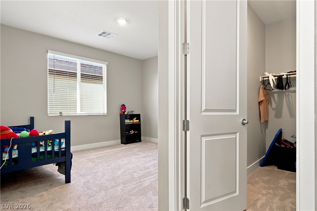 Soft carpeting pairs with neutral walls to create a peaceful secondary bedroom and adjacent closet.
