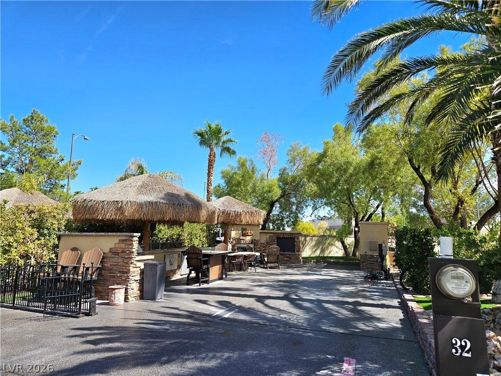 8175 Arville Street, #32, Las Vegas, NV 89139 Lush tropical palm trees frame a paved courtyard complete with a stone outdoor kitchen.