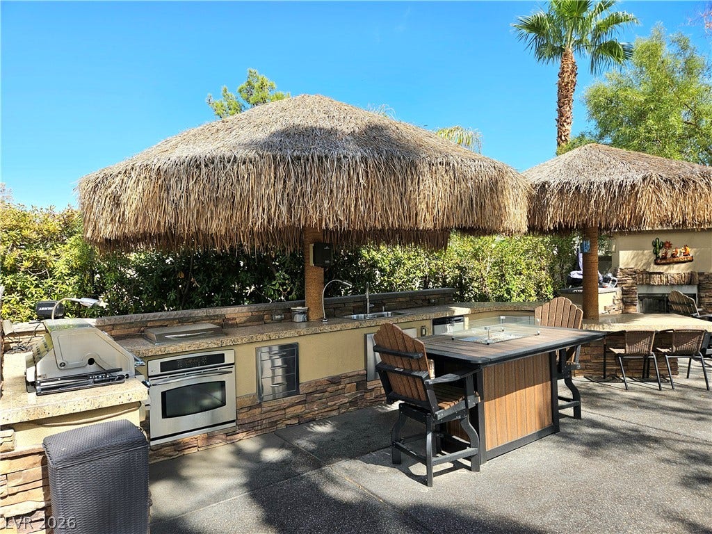 8175 Arville Street, #32, Las Vegas, NV 89139 A fully equipped stone outdoor kitchen stands beneath tropical palapas on a spacious patio.