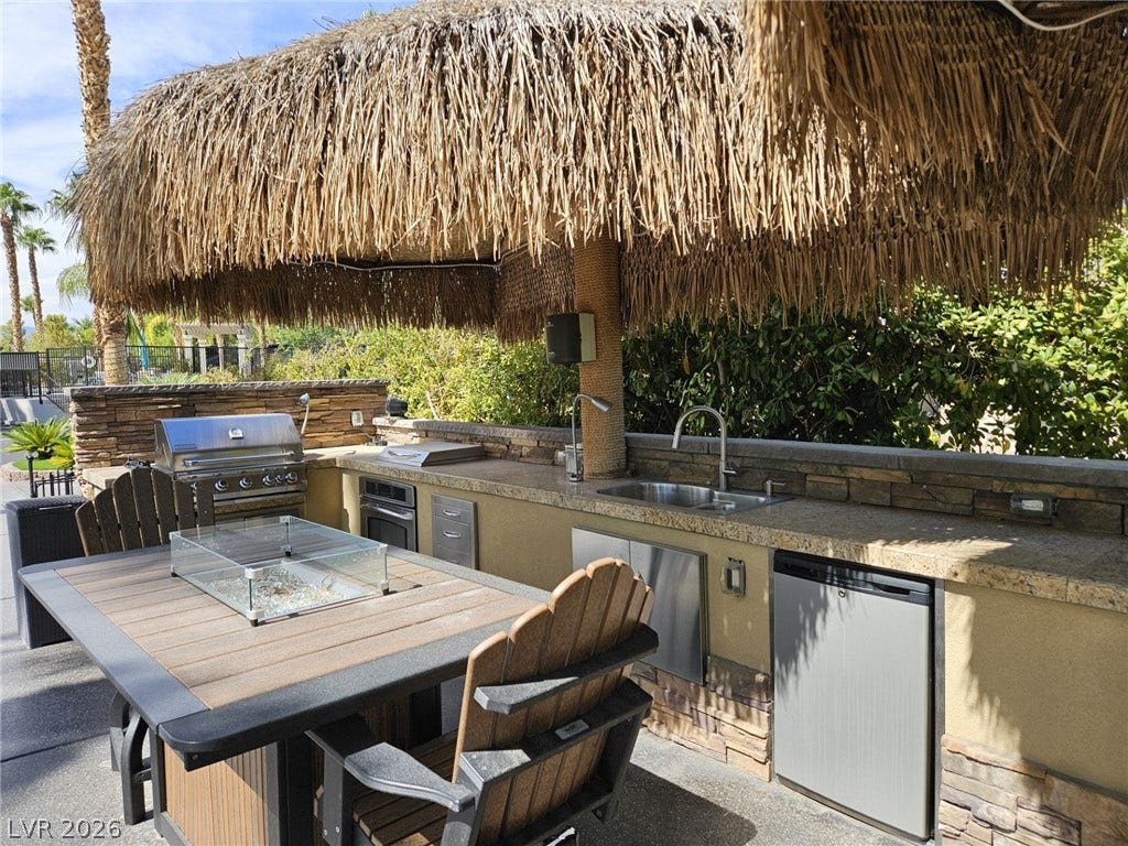 8175 Arville Street, #32, Las Vegas, NV 89139 An outdoor kitchen features stone counters and built-in appliances beneath a thatched roof.