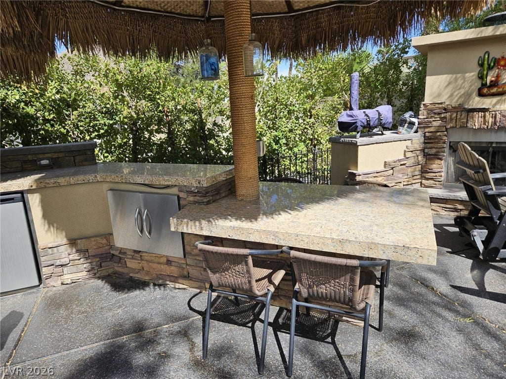 8175 Arville Street, #32, Las Vegas, NV 89139 Granite counters and stacked stone accents define this built-in outdoor kitchen with a thatched umbrella cover.
