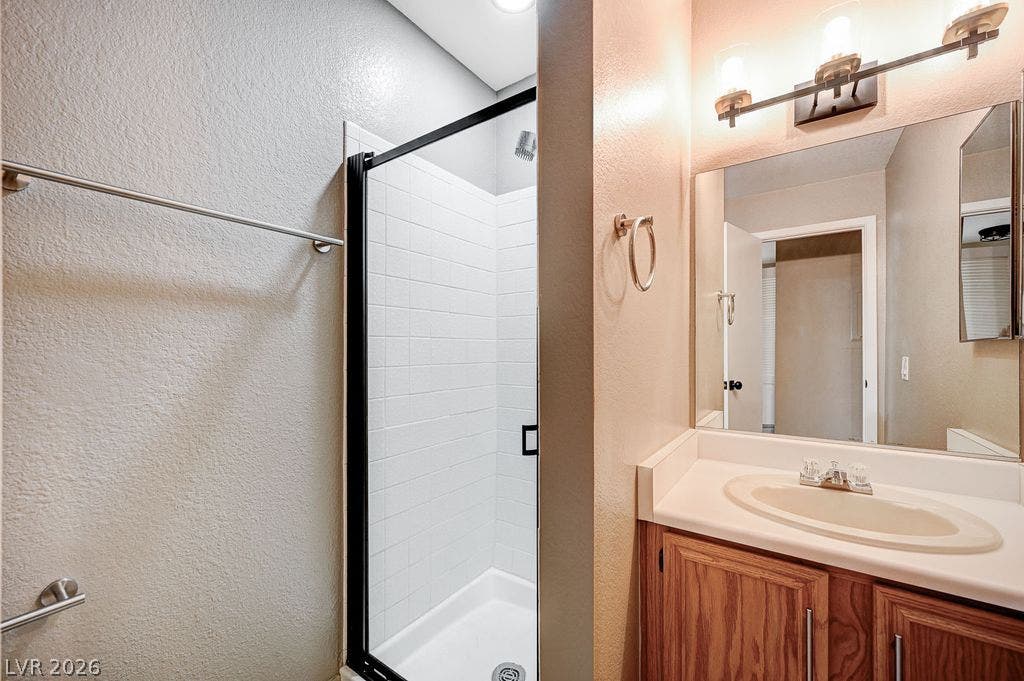 2191 Pinetop Lane, #104, Las Vegas, NV 89119 A classic vanity sits adjacent to a modern walk-in shower framed in black.