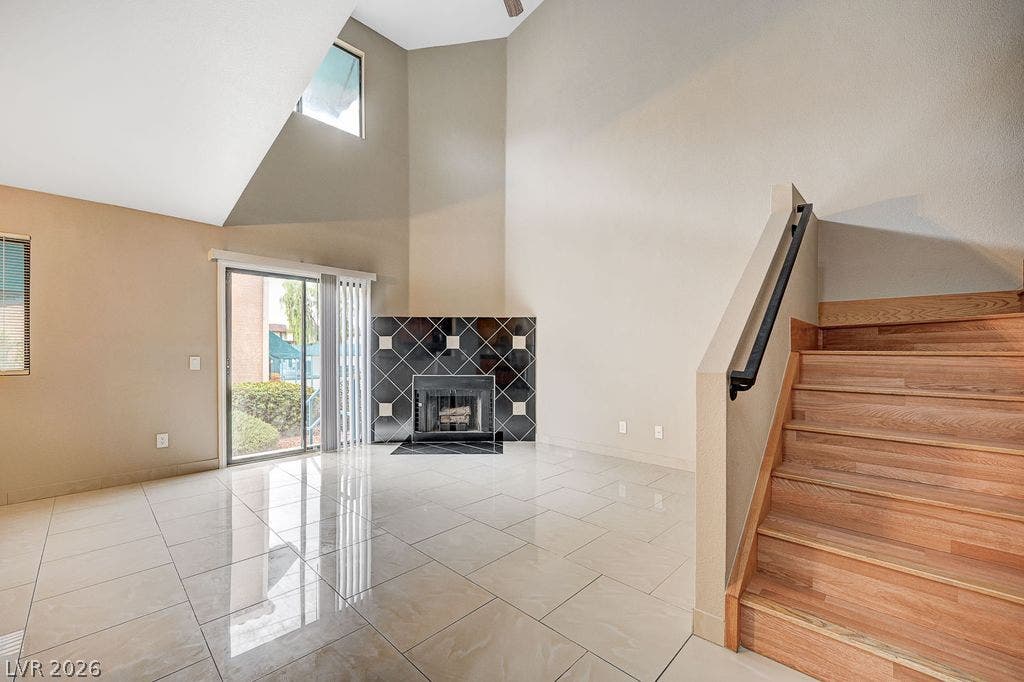 2191 Pinetop Lane, #104, Las Vegas, NV 89119 Polished tile flooring and soaring ceilings frame the focal fireplace in this open living space.