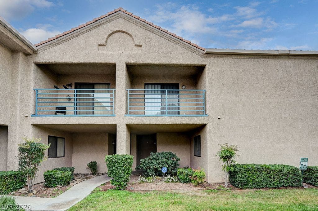 2191 Pinetop Lane, #104, Las Vegas, NV 89119 Upper-level balconies overlook a neatly landscaped courtyard entry under clear skies.