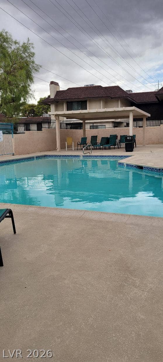 2191 Pinetop Lane, #104, Las Vegas, NV 89119 A fenced swimming pool area bordered by concrete decking features a covered cabana structure.
