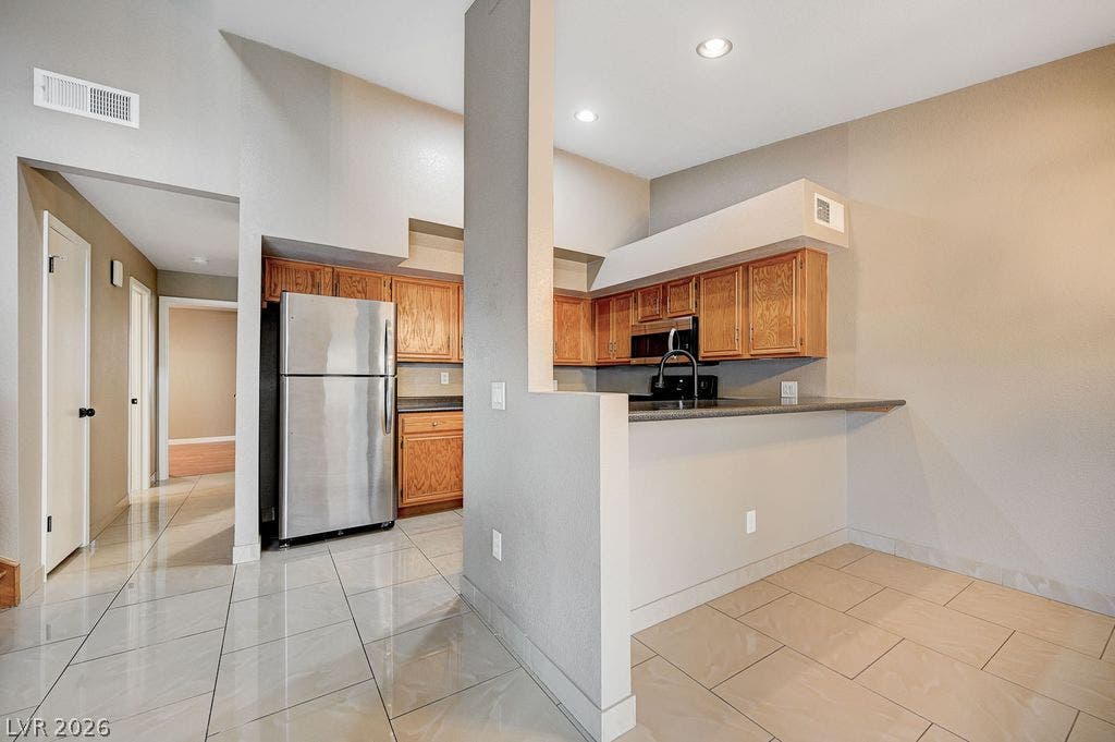2191 Pinetop Lane, #104, Las Vegas, NV 89119 Polished tile flooring and classic wood cabinetry define this open kitchen design.